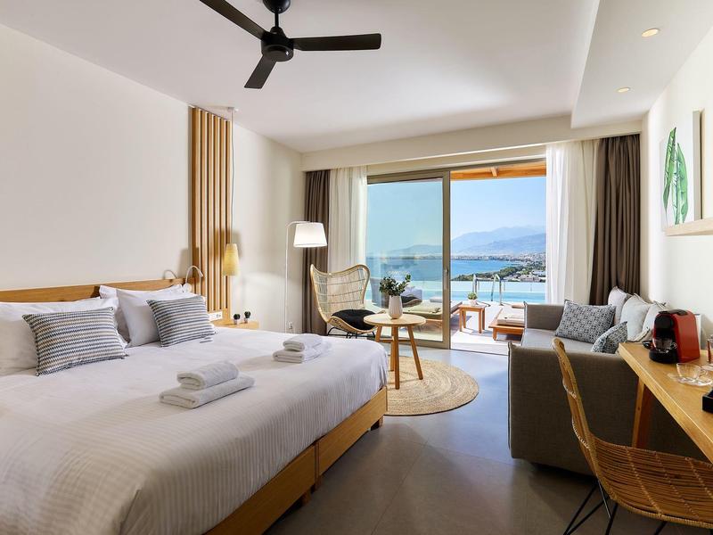 Moderní hotelový pokoj s velkou postelí, balkonem a výhledem na oceán.