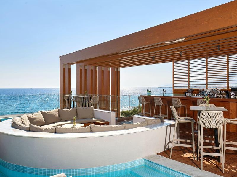 Venkovní lounge a bar s výhledem na oceán a moderním posezením u bazénu.