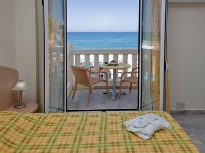 Vistas desde una habitación de hotel a un balcón con sillas y mesa con vista al mar.
