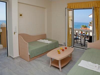 Habitación de hotel con dos camas y balcón con vistas al mar.