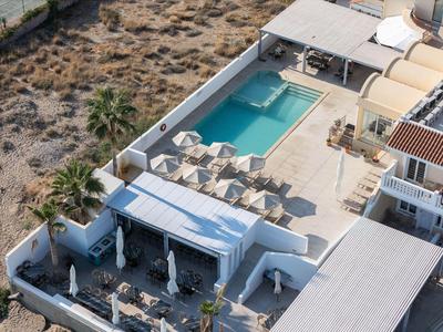 Vista aérea de un hotel con piscina, tumbonas y paisaje desértico circundante.