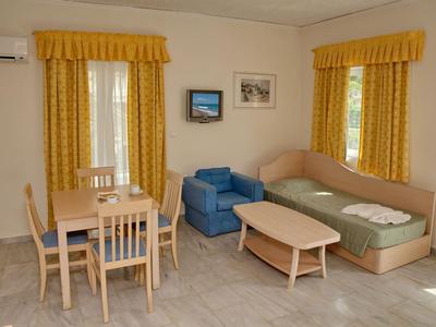 Acogedora sala con cortinas amarillas, mesa de comedor, sillón azul y sofá con mesa de centro.