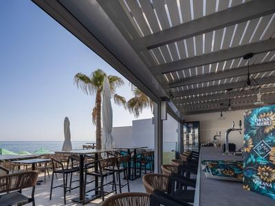 Terraza cubierta de hotel con zona de asientos y vista al mar bajo cielo despejado
