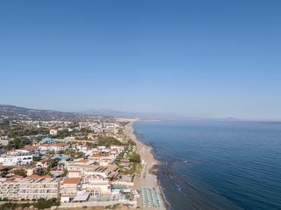 Vista aérea de una larga playa con casas y mar tranquilo en un día despejado.