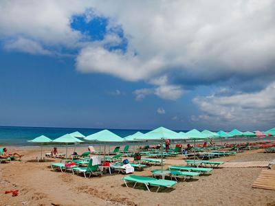 Playa con muchas tumbonas y sombrillas bajo un cielo nublado junto al mar.