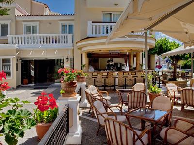 Terraza exterior soleada de un hotel con asientos y bar bajo sombrillas.