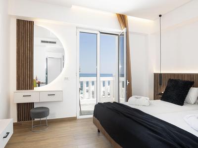 Habitación de hotel luminosa con cama, escritorio, balcón y vista al mar