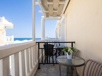 Balcón con zona de estar y vista al mar en un día soleado.