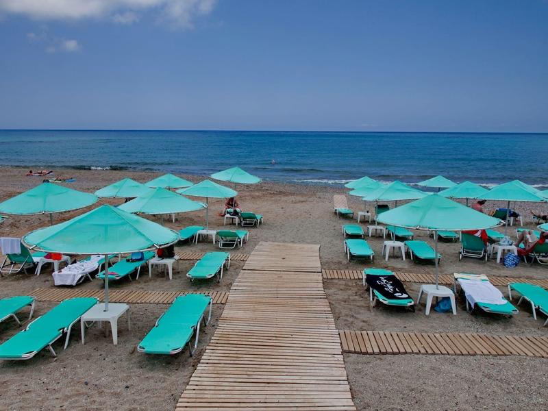 Plaża z turkusowymi leżakami i parasolami, widok na spokojne morze.