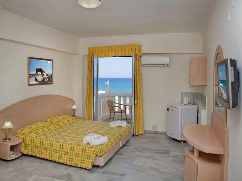 Jasny pokój hotelowy z łóżkiem podwójnym i balkonem z widokiem na morze.