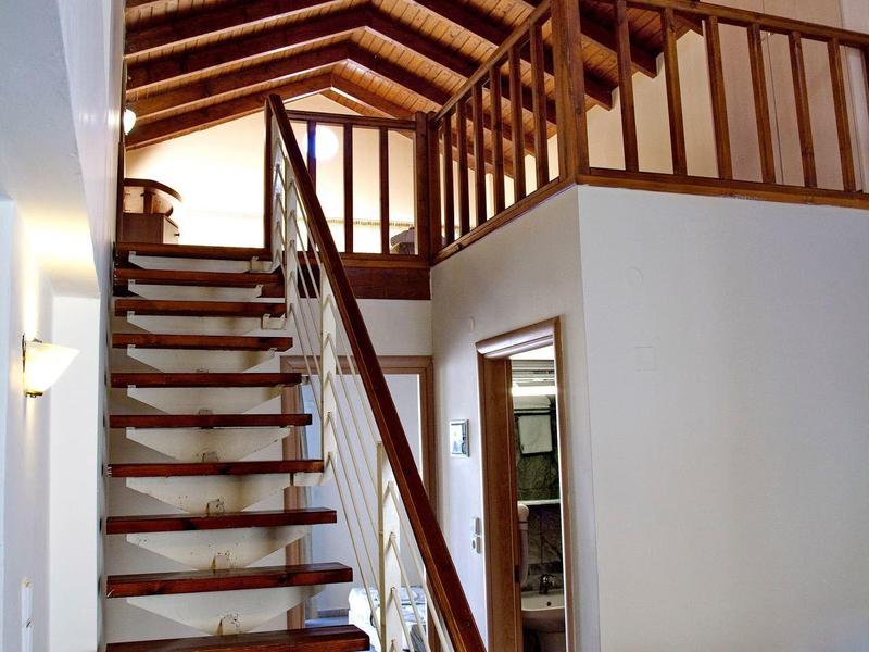 Nowoczesne wnętrze z schodami prowadzącymi na otwarte poddasze i drewniane belki