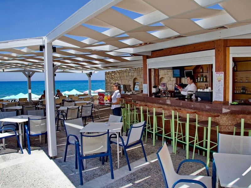 Otwarta kawiarnia na plaży z miejscami do siedzenia i barem z widokiem na morze.