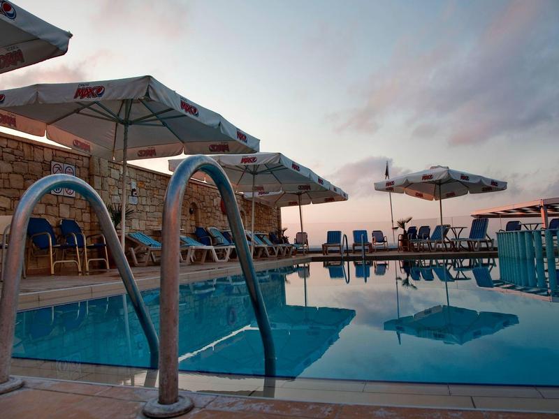 Spokojny basen z leżakami i parasolami o zachodzie słońca.