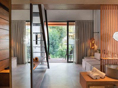 Chambre d'hôtel moderne avec balcon, lit et salle de bain en concept ouvert.