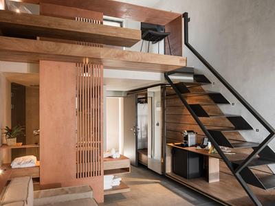 Intérieur d'une chambre d'hôtel moderne avec escalier en bois, bureau et mobilier élégant.