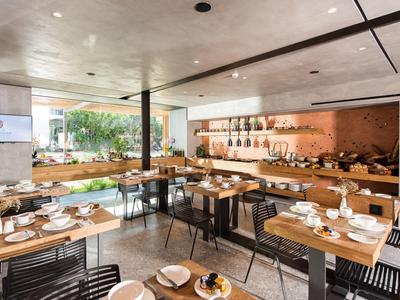 Sala da pranzo moderna con tavoli in legno, sedie e tavoli apparecchiati.