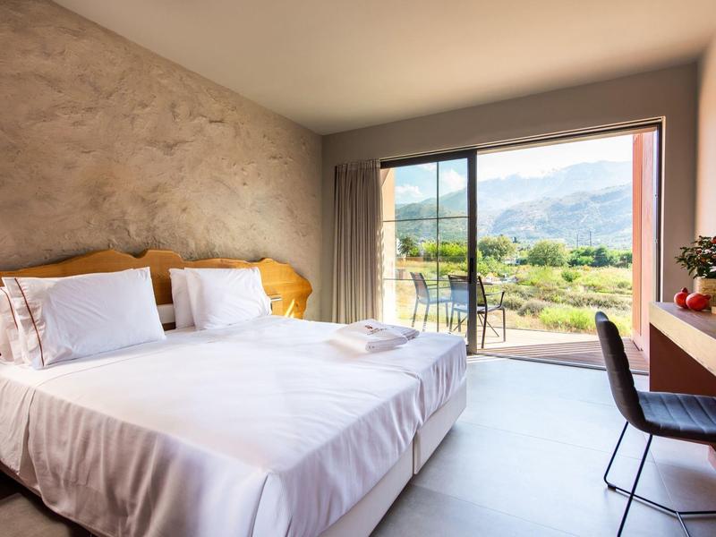Chambre d'hôtel lumineuse avec grand lit et vue sur la montagne à travers de grandes fenêtres