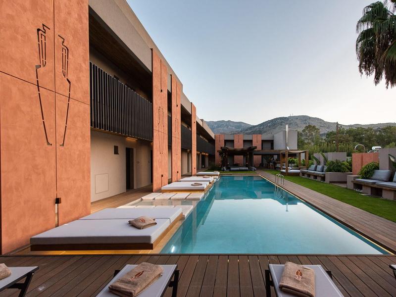 Espace piscine extérieur moderne avec transats près d’un bâtiment dans un environnement ensoleillé avec montagnes