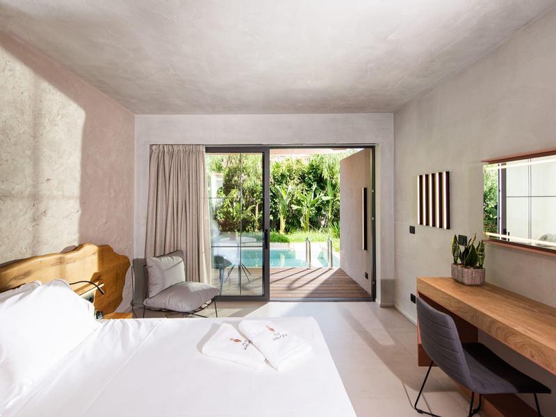Chambre d'hôtel lumineuse avec lit double, bureau et vue sur la piscine à travers la porte coulissante en verre.