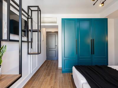 Modern hotelkamer met blauwe kledingkast, houten vloer en minimalistisch ontwerp.