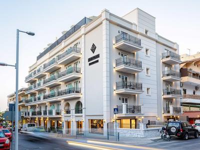Modern wit hoekgebouw met balkons en hotelschilden op een straathoek.