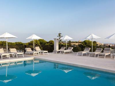 Pool area with white umbrellas and loungers under clear sky