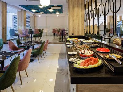 Modern dining area with various tables and a buffet featuring fruits and snacks.