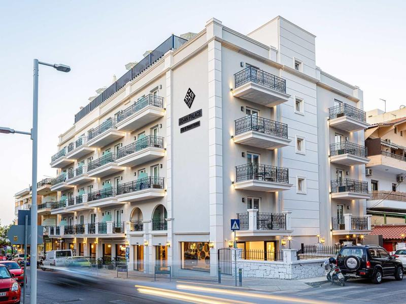 Modern wit hoekgebouw met balkons en hotelschilden op een straathoek.