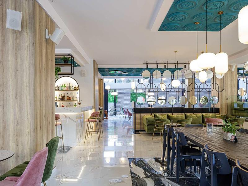 Modern ontworpen hotel-lounge met zitplaatsen, lampen en groen gedecoreerde muren.