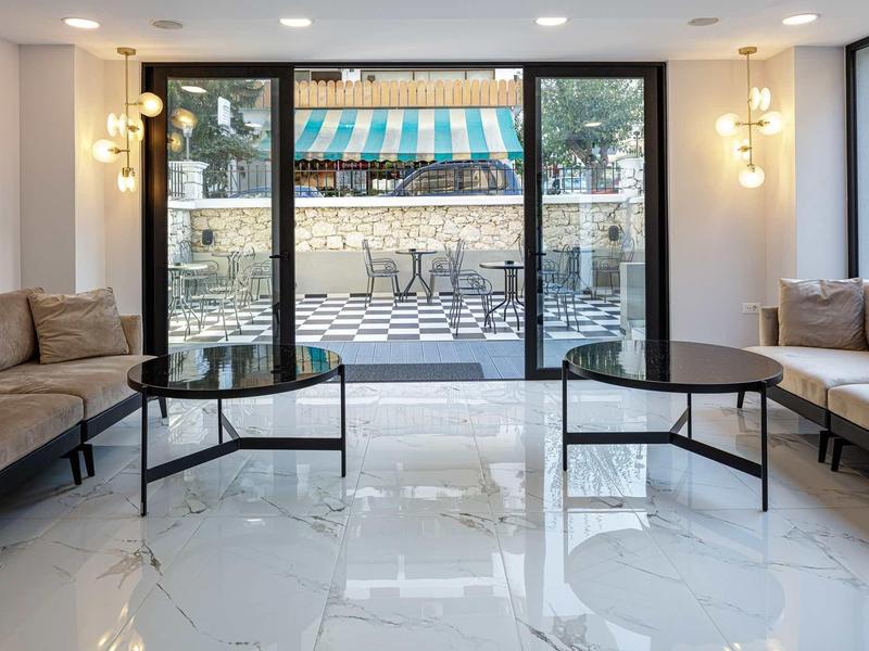 Moderne hotel lounge met banken en uitzicht op terras met kleurrijke luifel