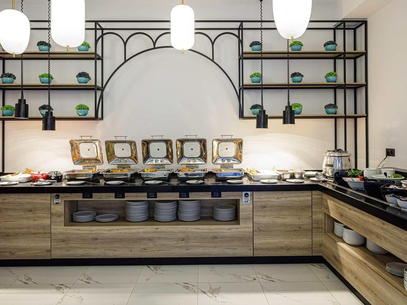 Modern buffet met eten in een stijlvol hotelrestaurant met houten planken en lampen.