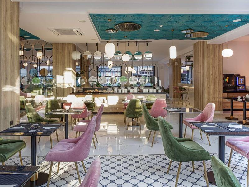 Modern ingericht hotel eetzaal met kleurrijke stoelen en gezellige sfeer.