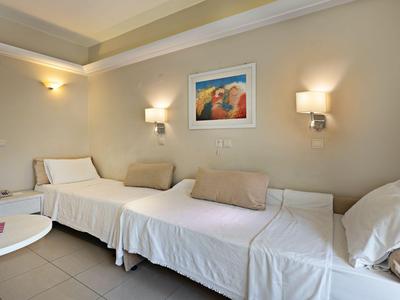 Une chambre d'hôtel avec deux lits, des coussins doux et un éclairage mural chaud.
