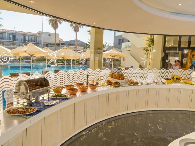 Buffet table with various breads and pastries near a poolside at a hotel.