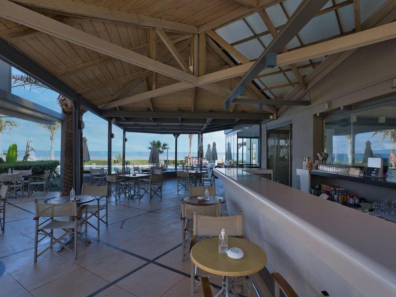 Outdoor bar area with stools, tables, and chairs under a wooden canopy with city views.
