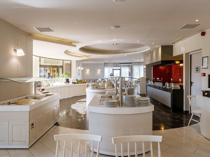 Spacious hotel buffet area with white decor and seating.