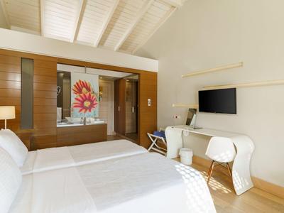 Habitación de hotel moderna con cama doble, paneles de madera y televisor de pantalla plana en la pared.