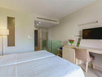 Habitación de hotel luminosa con dos camas, escritorio con televisor e interior minimalista.