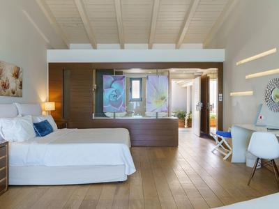 Habitación de hotel moderna y luminosa con cama doble, suelo de madera y decoración elegante.