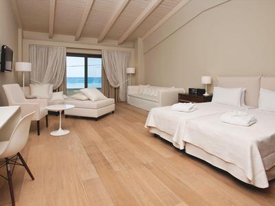 Jasny pokój hotelowy z dwoma pojedynczymi łóżkami, biurkiem i widokiem na morze.