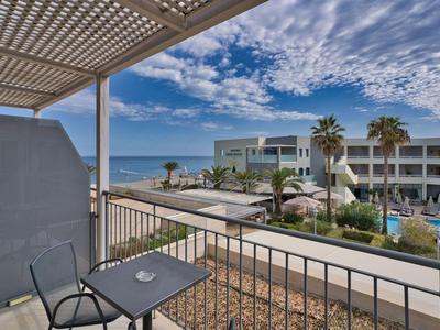 Widok z balkonu z krzesłem na hotel i morze pod pochmurnym niebem.