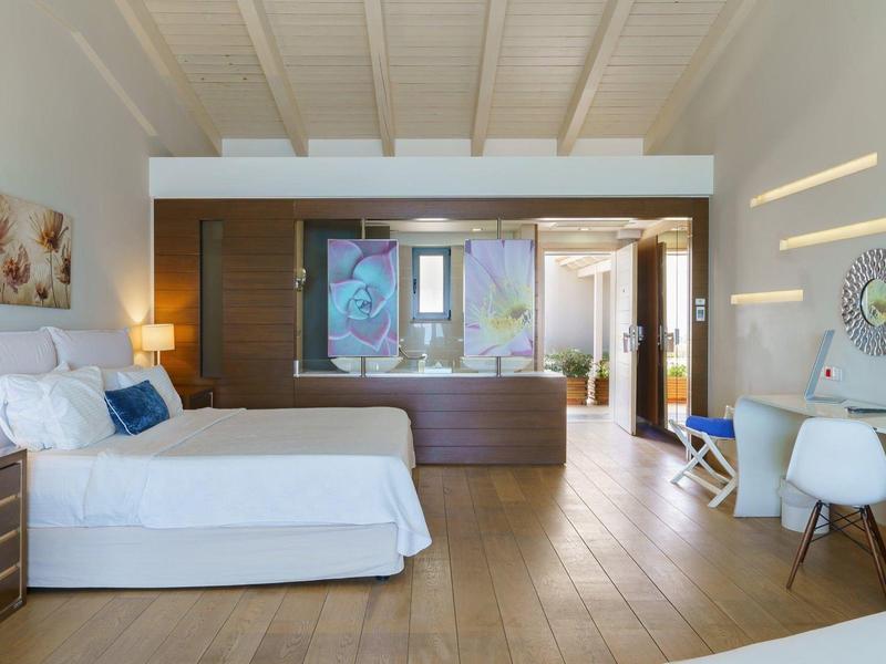 Ruime hotelkamer met twee bedden, houten vloer, moderne inrichting en grote spiegel aan de muur.