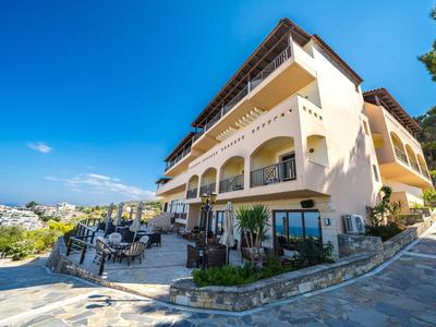 Velký hotel s balkony a terasou pod jasnou oblohou na slunném místě.