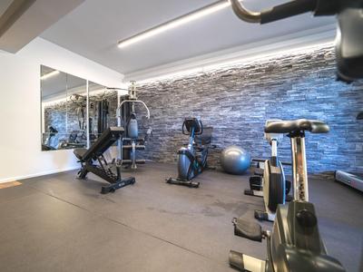 Moderní fitness místnost s vybavením a velkou zrcadlovou stěnou v hotelu.