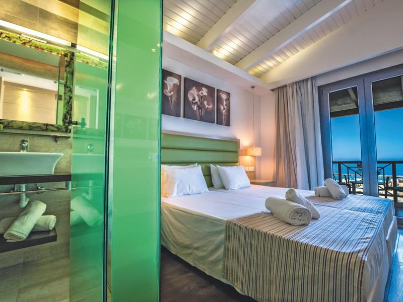 Modernes Schlafzimmer mit Doppelbett, Bad und Balkon mit Meerblick.