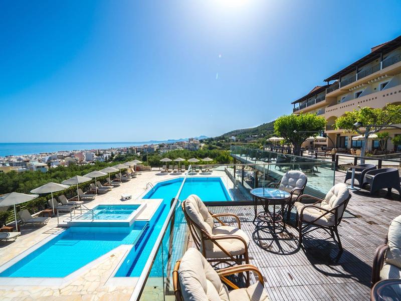 Luxuriöser Außenpoolbereich mit Meerblick, Liegestühlen und Sonnenschirmen an einem sonnigen Tag.