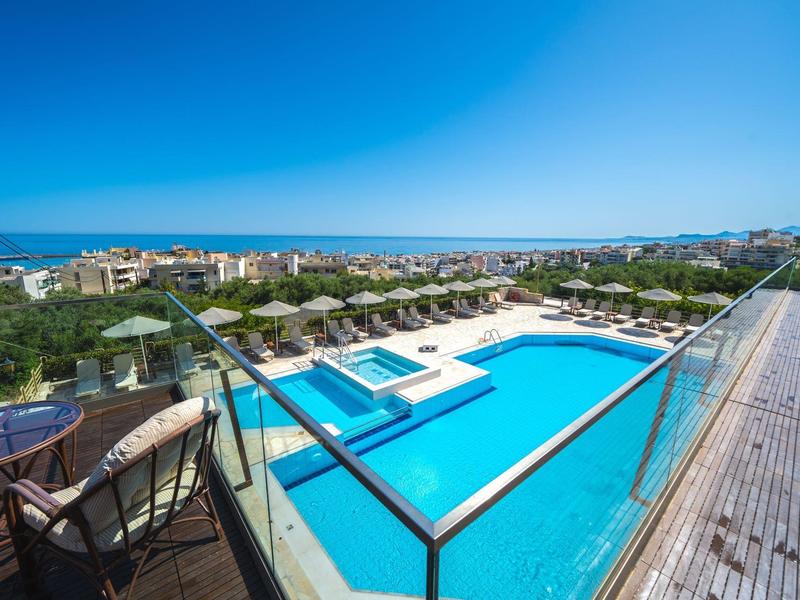 Großer Außenpool mit Liegestühlen und Meerblick an einem sonnigen Tag.