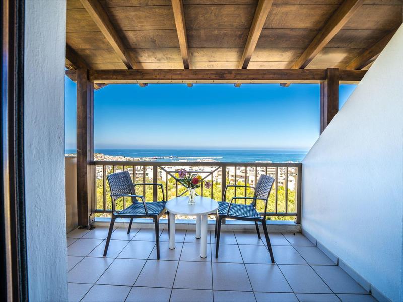Balkon mit zwei Stühlen, Tisch und Hängematte mit Meerblick unter Holzdach.