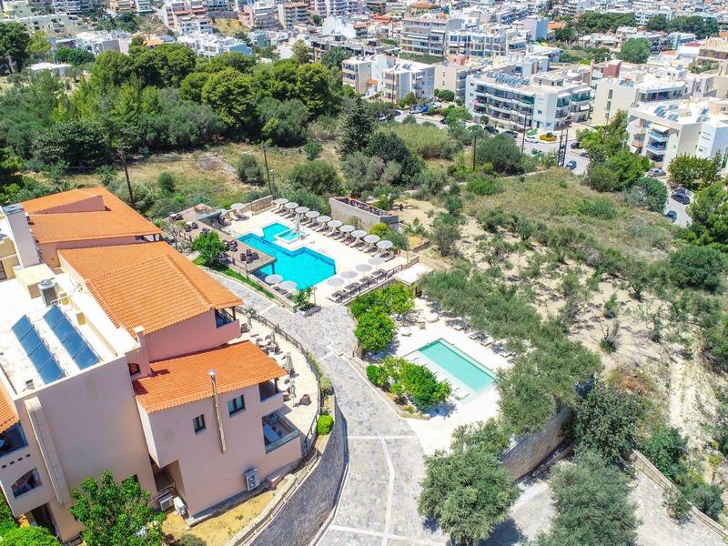 Luftaufnahme eines Hotels mit zwei Pools und umgeben von Grünflächen in einer Stadt.