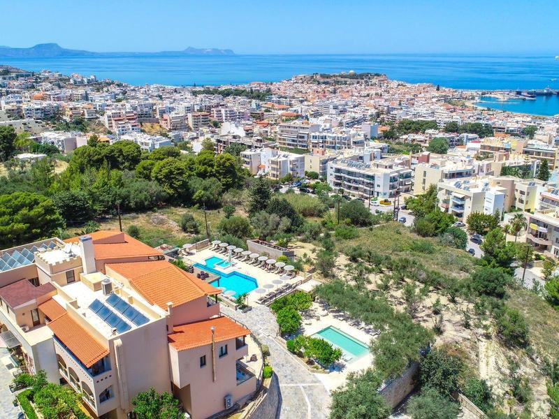 Luftaufnahme von Häusern, grünem Gelände und Meer in der Ferne an der Küste.